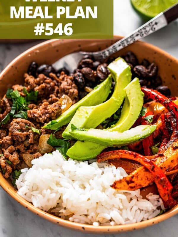 A taco bowl filled with taco fixings, including browned ground beef, rice, avocado, black beans, and peppers.