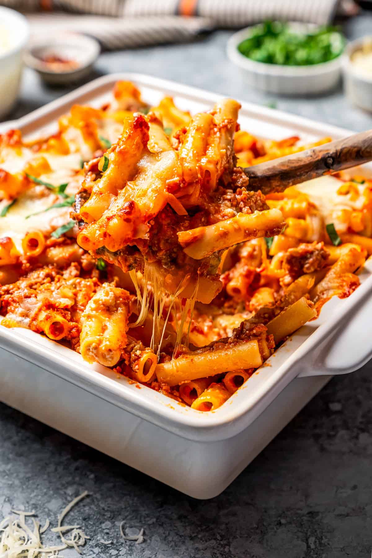 My easy baked ziti recipe is a weeknight-friendly pasta casserole with rich homemade meat sauce and three kinds of melty Italian cheese. A spoon scooping cheesy baked ziti from a baking dish.