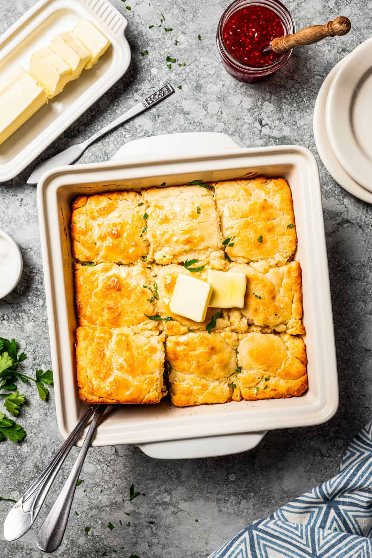 Butter swim biscuits are fluffy drop biscuits baked in a pool of butter! Crispy outside, soft inside, and easy to make with 5 ingredients. Butter swim biscuits topped with pats of butter in a square baking dish.