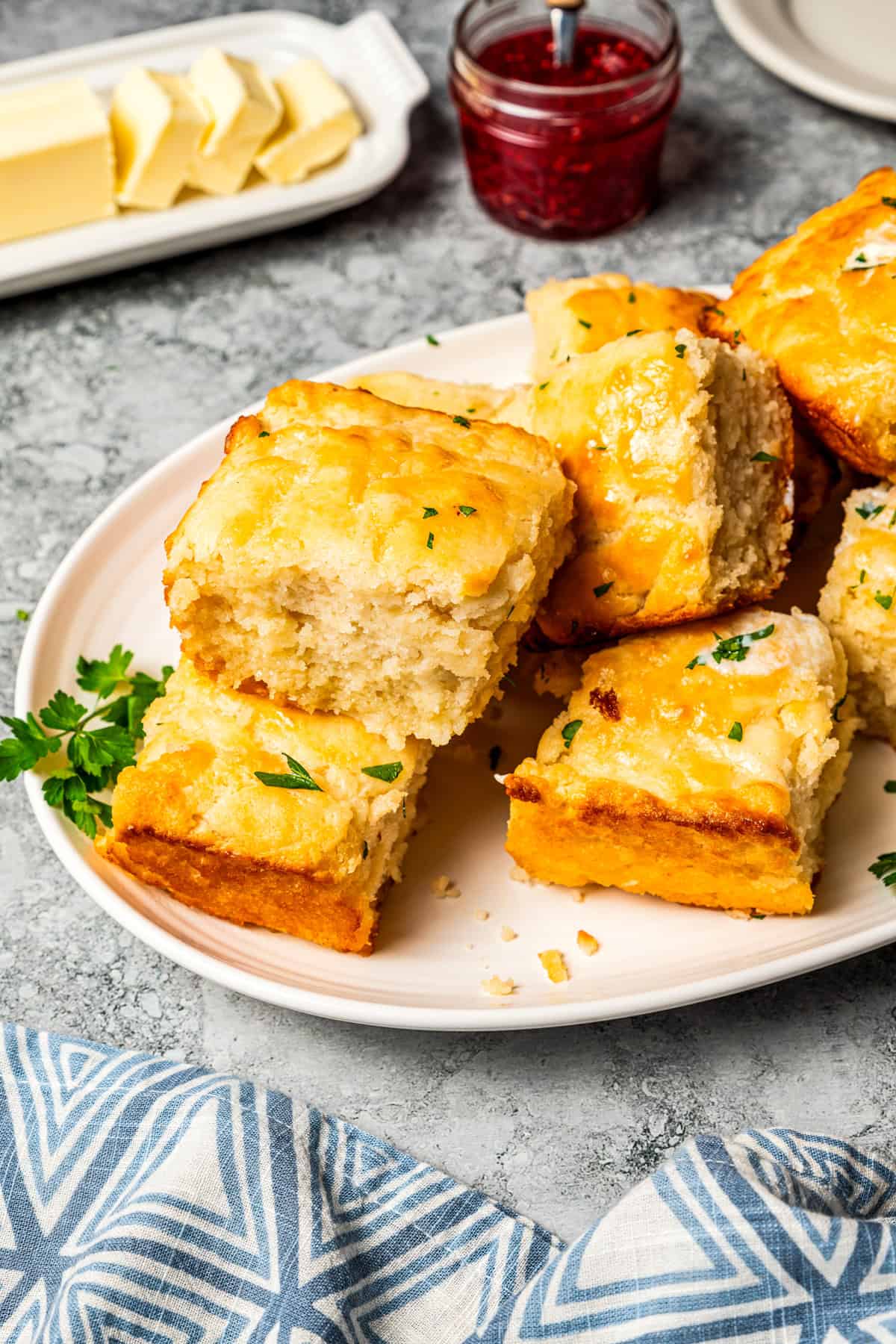 Butter swim biscuits are fluffy drop biscuits baked in a pool of butter! Crispy outside, soft inside, and easy to make with 5 ingredients. Butter swim biscuits stacked on a platter.