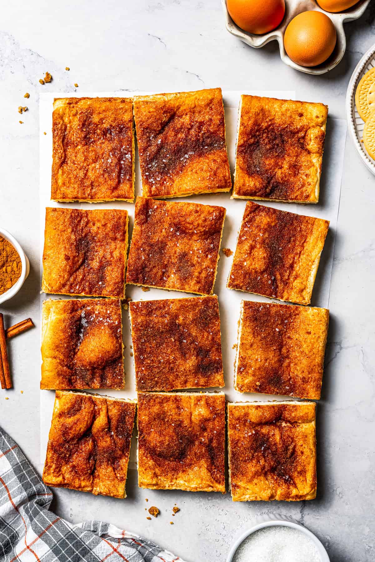 This churro cheesecake bars recipe is an easy dessert with layers of cinnamon sugar, a flaky pastry crust, and creamy cheesecake filling. Overhead view of churro cheesecake bars cut into squares.