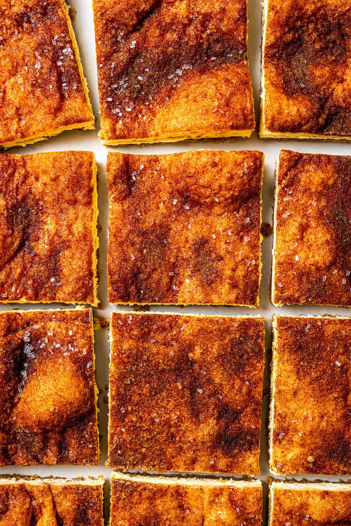 This churro cheesecake bars recipe is an easy dessert with layers of cinnamon sugar, a flaky pastry crust, and creamy cheesecake filling. Cheesecake bars cut into squares.