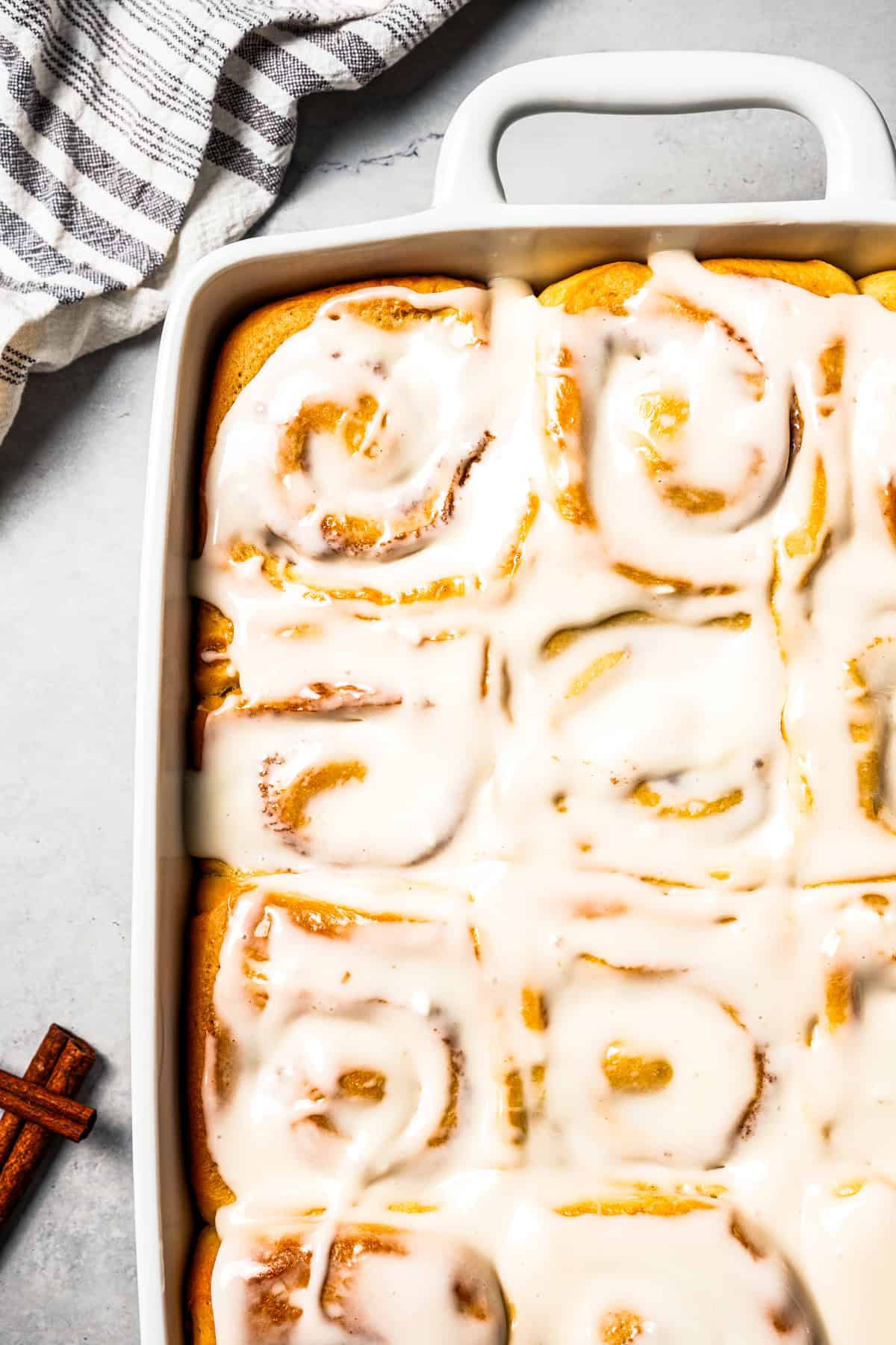 This cinnamon roll recipe makes big, bakery-style cinnamon buns filled with gooey cinnamon sugar and topped with sweet cream cheese frosting. Frosted cinnamon rolls in a baking dish.