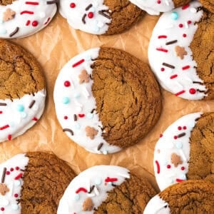 Rows of gingerbread cookies with one half of each cookie covered in melted white chocolate and decorated with sprinkles.