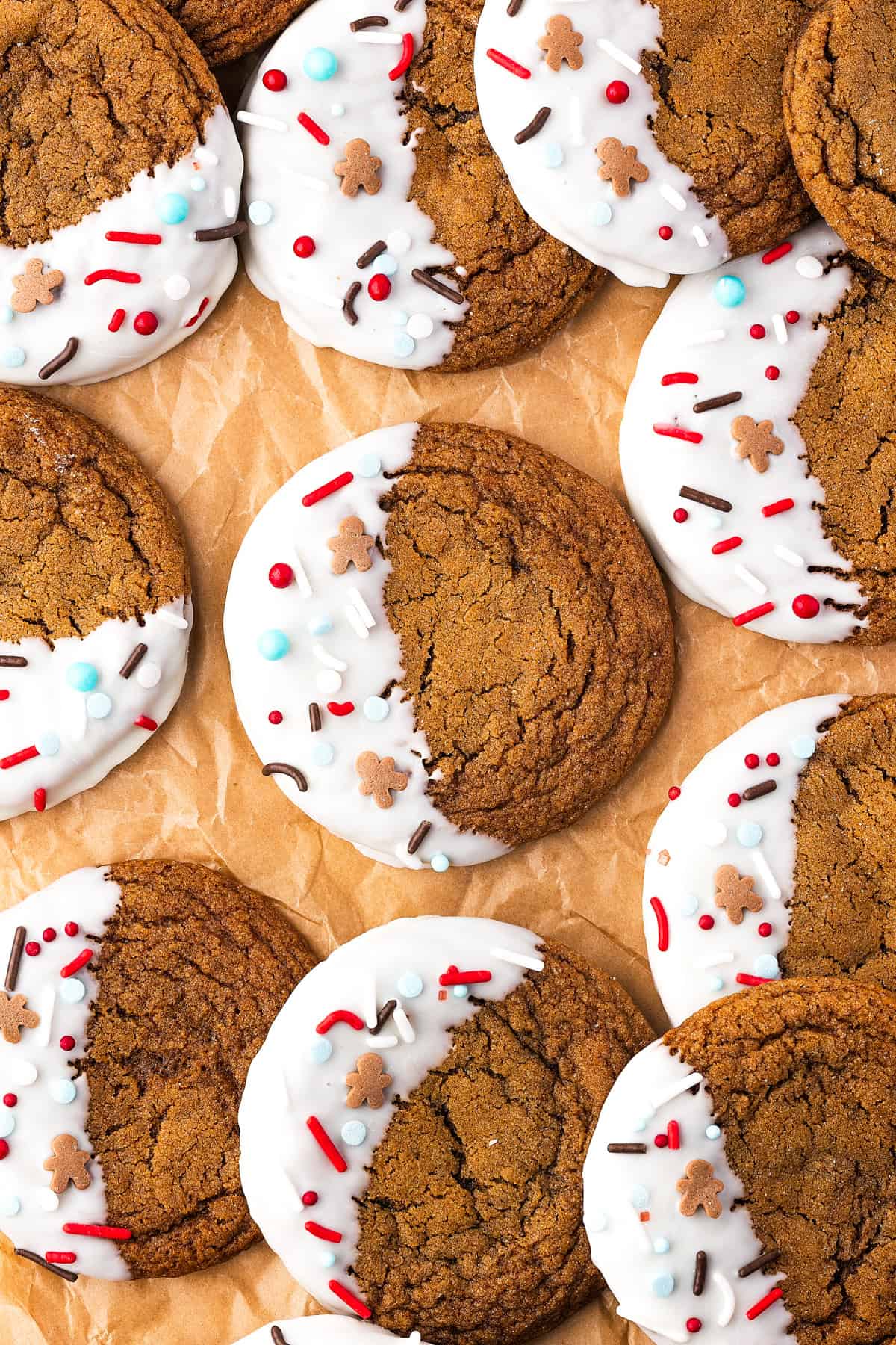 Thick, chewy, and soft gingerbread cookies flavored with warm spices and molasses. They're festive, cozy, and so easy to make for the holidays. Rows of gingerbread cookies with one half of each cookie covered in melted white chocolate and decorated with sprinkles.