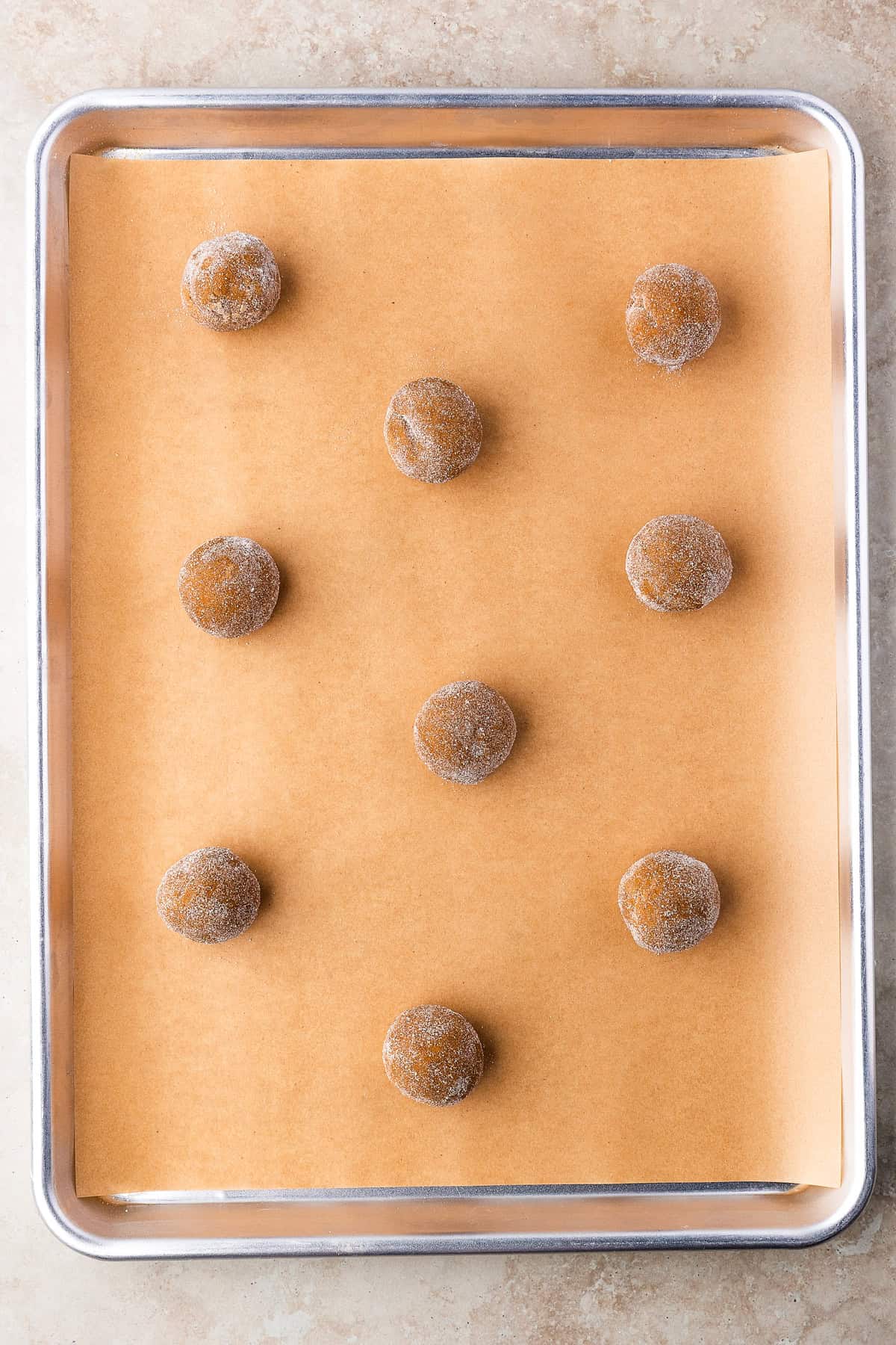 Thick, chewy, and soft gingerbread cookies flavored with warm spices and molasses. They're festive, cozy, and so easy to make for the holidays. Balls of cookie dough on a parchment lined baking sheet.
