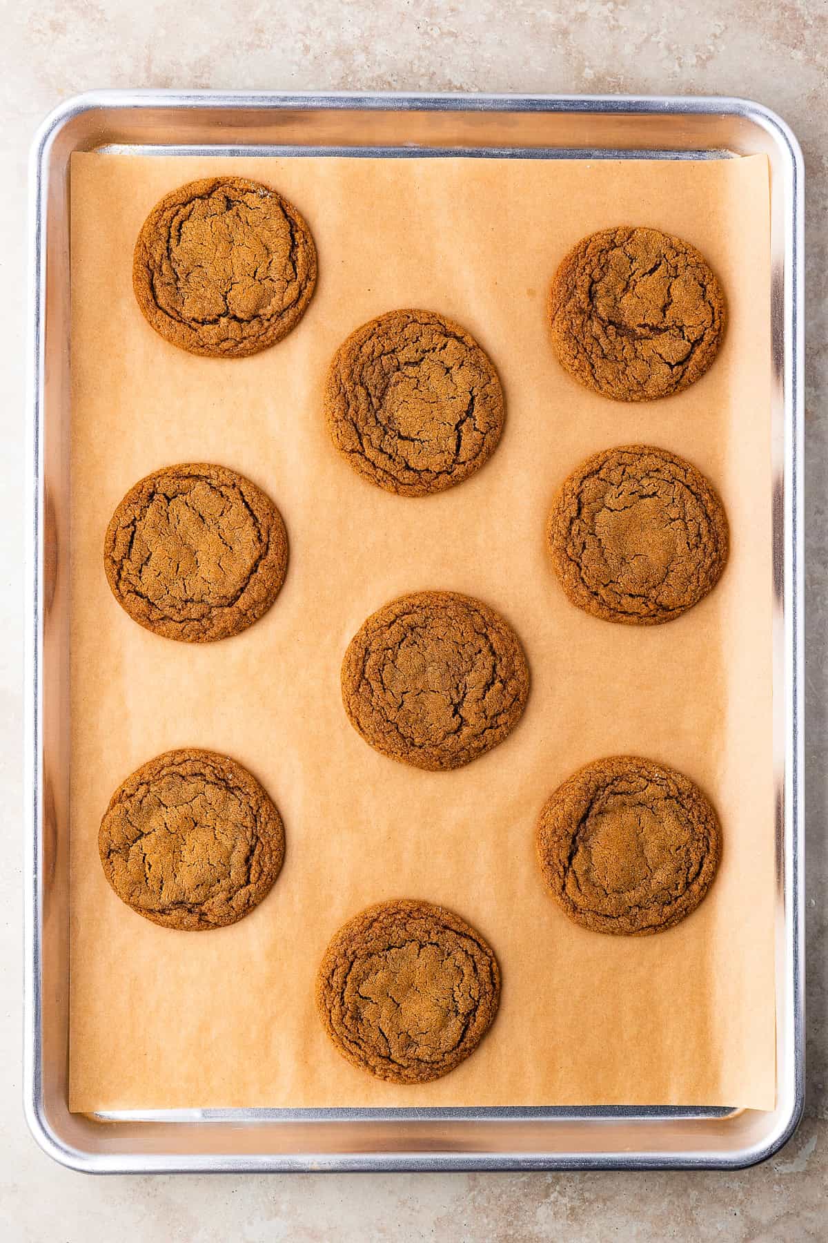 Thick, chewy, and soft gingerbread cookies flavored with warm spices and molasses. They're festive, cozy, and so easy to make for the holidays. Baked gingerbread cookies on a baking sheet lined with parchment.