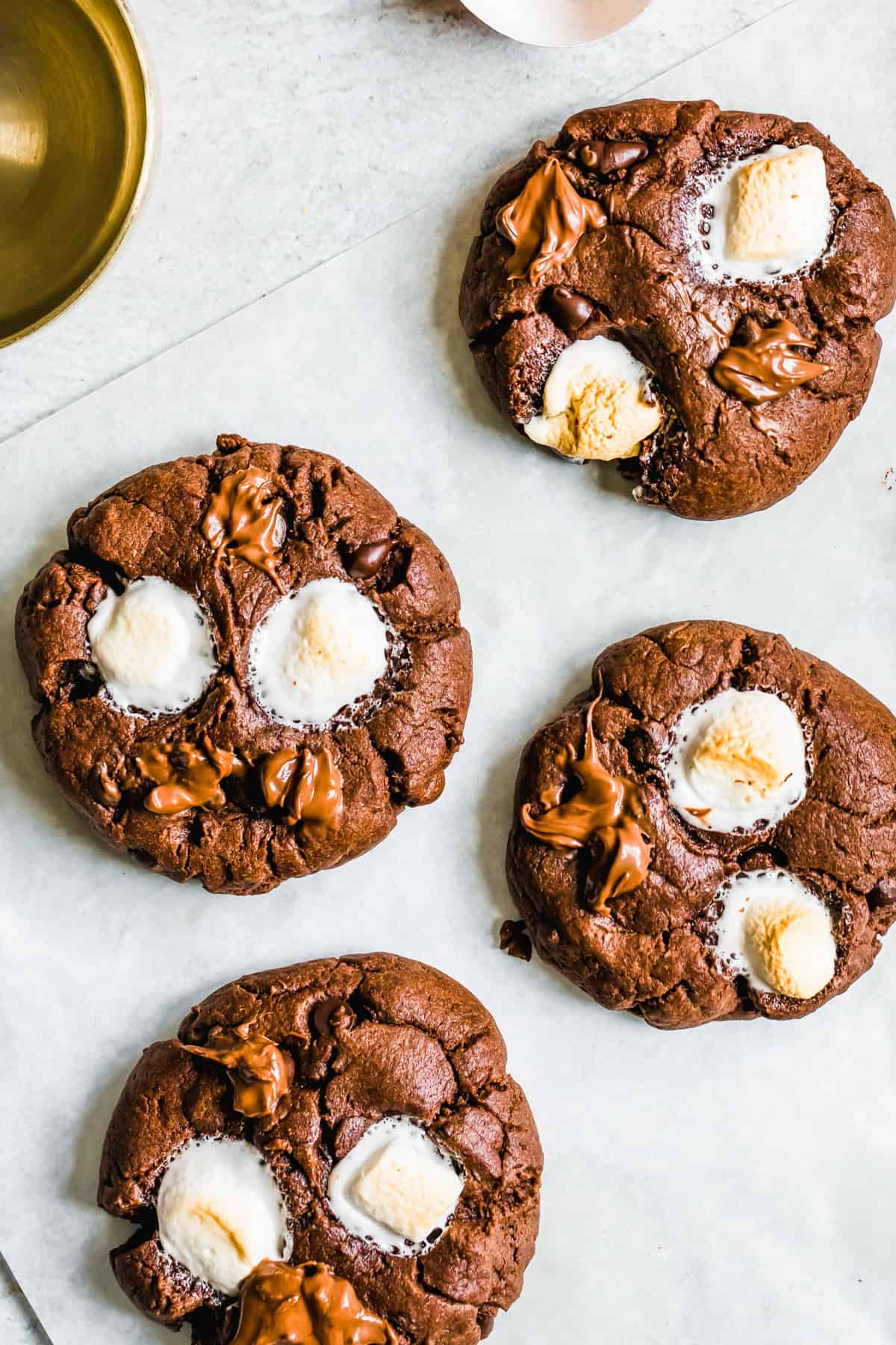 Four chocolate cookies topped with melty marshmallows.