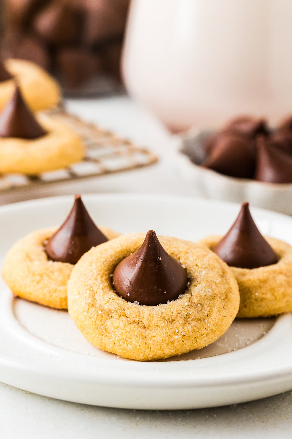 This peanut butter blossoms recipe makes soft, thick peanut butter cookies topped with a chocolate kiss. Easy to make and perfect for any occasion. A plate of peanut butter blossoms with a Hershey's kiss.