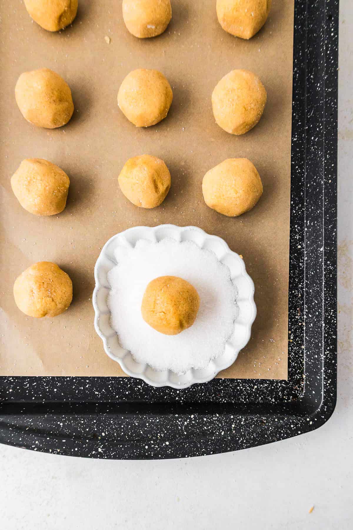 This peanut butter blossoms recipe makes soft, thick peanut butter cookies topped with a chocolate kiss. Easy to make and perfect for any occasion. Rows of cookie dough balls on a baking sheet.
