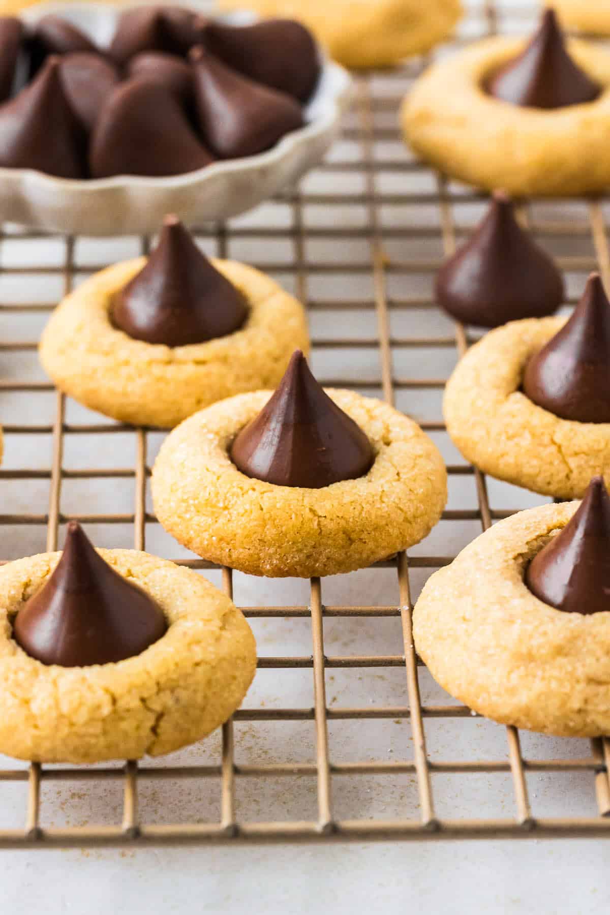 This peanut butter blossoms recipe makes soft, thick peanut butter cookies topped with a chocolate kiss. Easy to make and perfect for any occasion. Peanut butter blossoms on a wire rack.