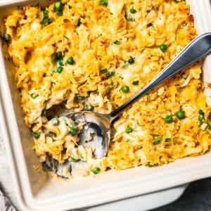 A spoon resting in the corner of a tuna casserole in a baking dish.
