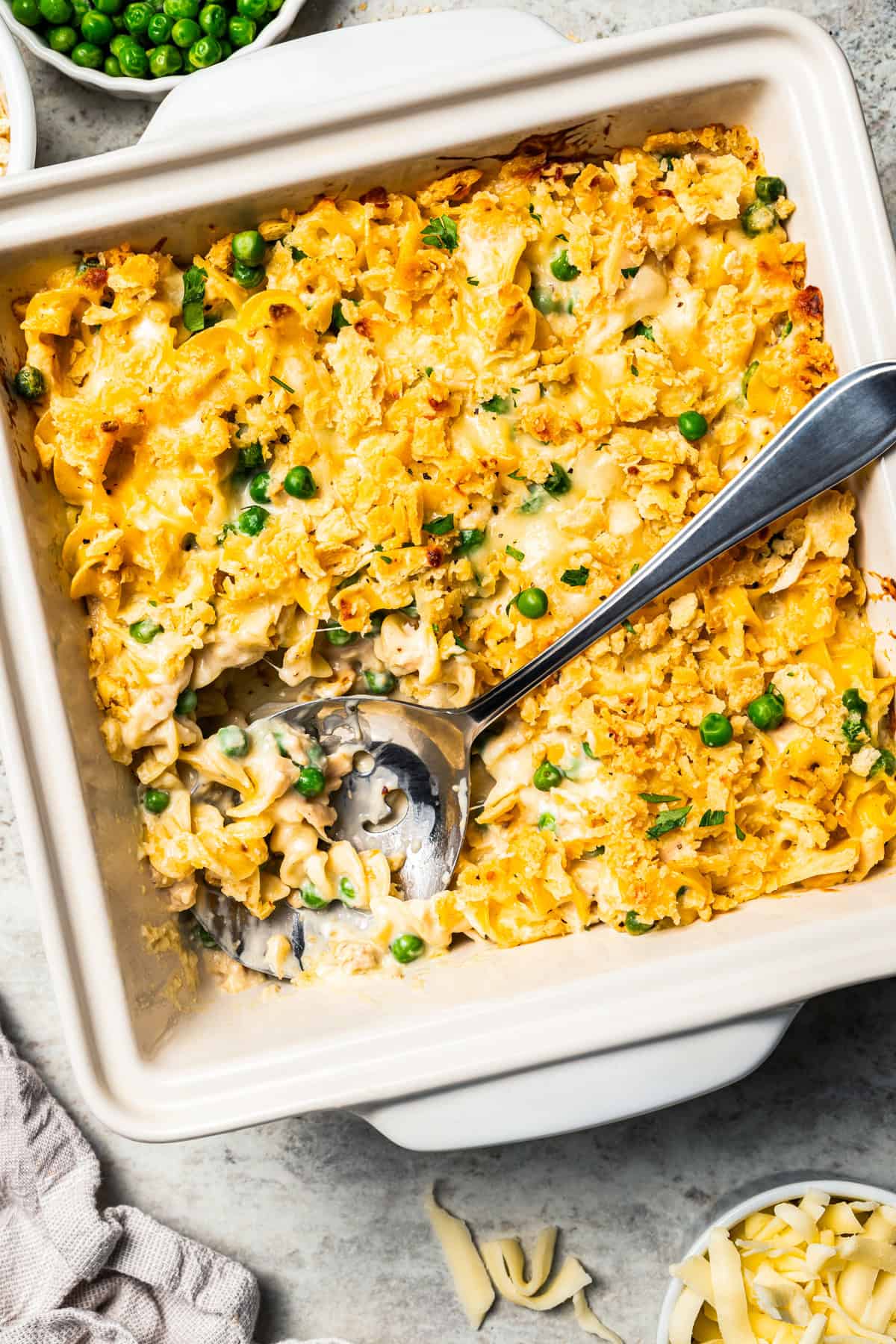 A spoon resting in the corner of a tuna casserole in a baking dish.