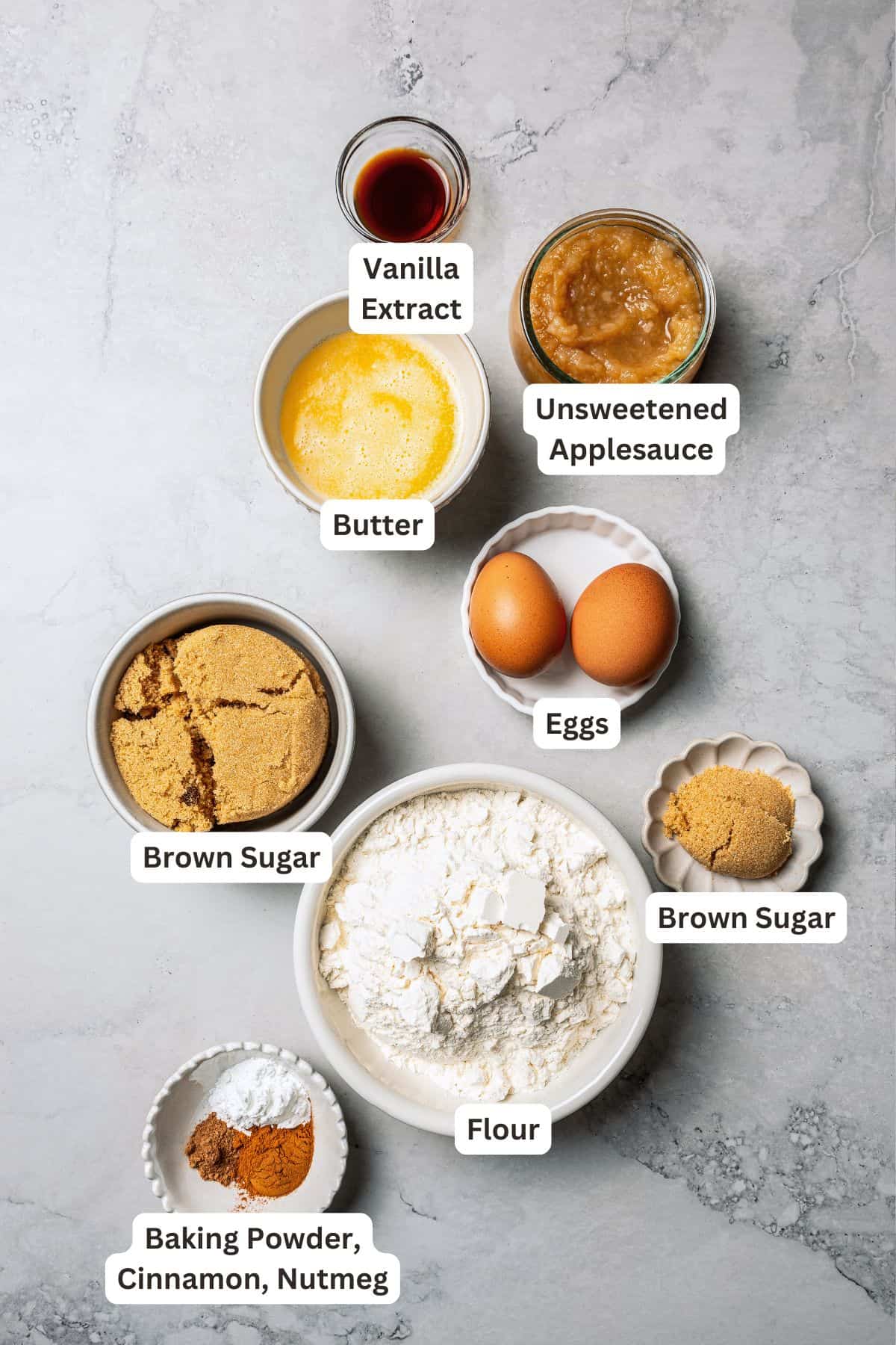 These moist applesauce muffins are easy to make and are packed with brown sugar and cinnamon, topped with extra sugar for a crunchy finish! Applesauce muffins ingredients with text labels overlaying each ingredient.