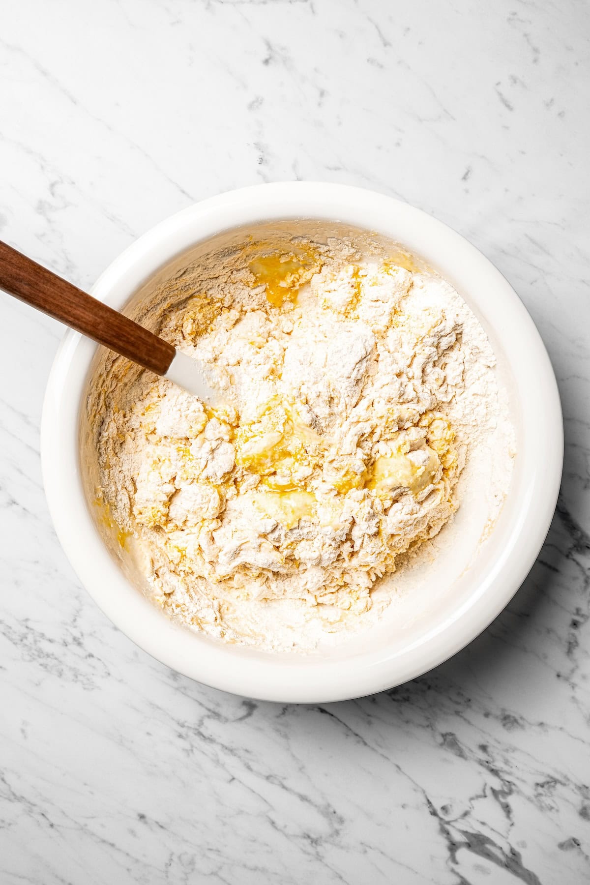 Adding the wet ingredients to a bowl of dry dough ingredients.