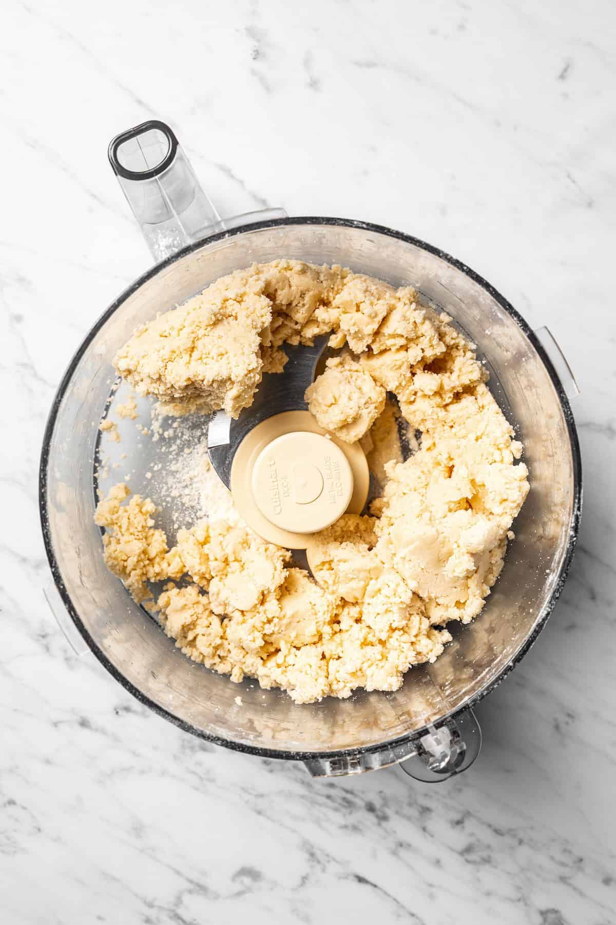 This easy coconut cream pie recipe features a thick, creamy coconut filling topped with fresh whipped cream in a golden, flaky pie crust. Pie crust mixture inside a food processor.