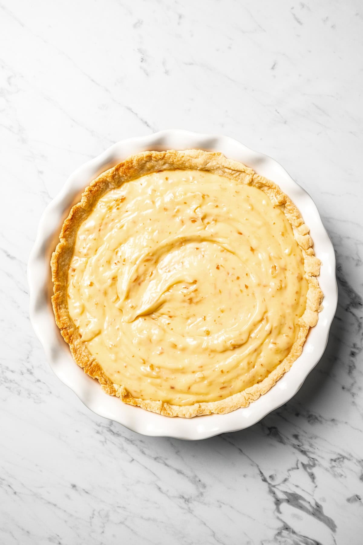 This easy coconut cream pie recipe features a thick, creamy coconut filling topped with fresh whipped cream in a golden, flaky pie crust. Coconut cream pie filling in a pie crust.