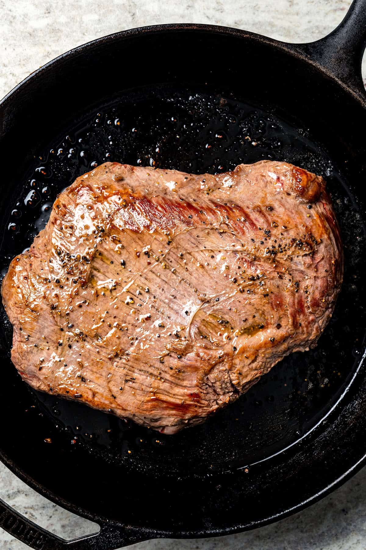 Crock pot carne asada has smoky spices and bright citrus, soaked into juicy shredded steak. Only 5 minutes to prep and perfect for tacos! Seared flank steak in a skillet.