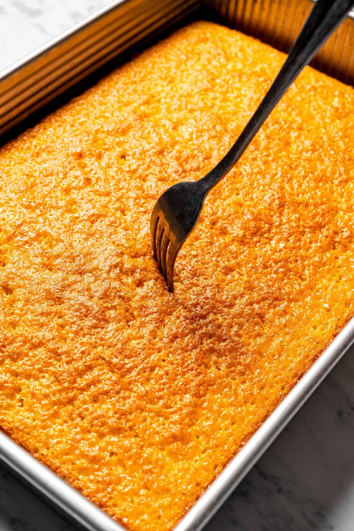 This authentic Mexican tres leches cake is a light, spongy cake soaked in a sweet milk mixture and topped with fluffy homemade whipped cream. Using a fork to poke holes all over the top of a baked cake.