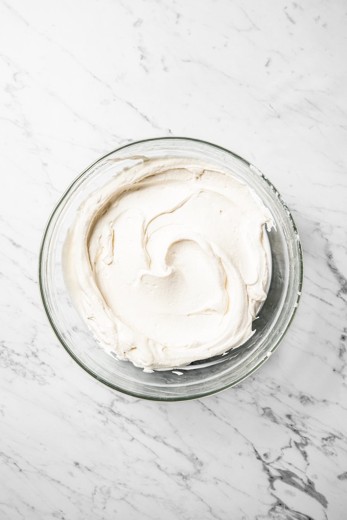 This authentic Mexican tres leches cake is a light, spongy cake soaked in a sweet milk mixture and topped with fluffy homemade whipped cream. Whipped cream topping in a bowl.