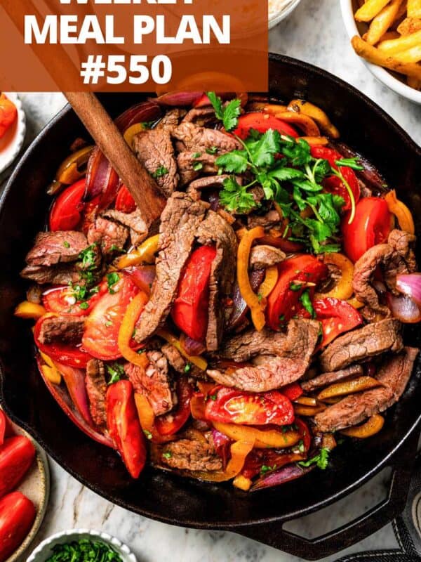 Slices of beef with sliced bell peppers and tomatoes in a skillet, preparing Lomo Saltado.