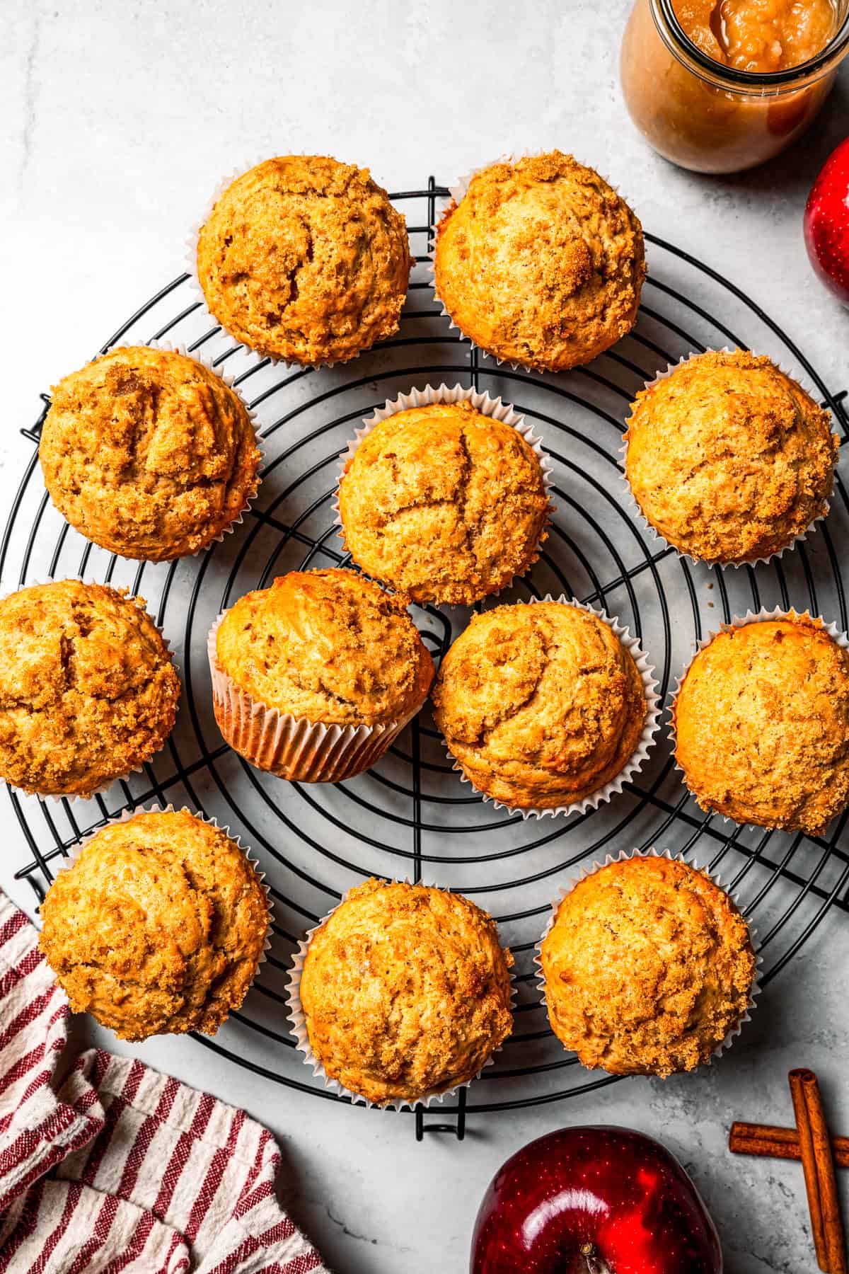 These moist applesauce muffins are easy to make and are packed with brown sugar and cinnamon, topped with extra sugar for a crunchy finish! Applesauce muffins arranged on a round wire rack.