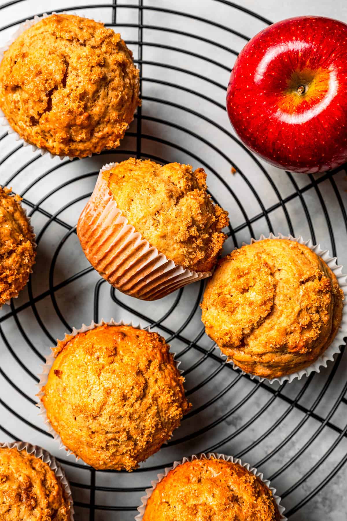 These moist applesauce muffins are easy to make and are packed with brown sugar and cinnamon, topped with extra sugar for a crunchy finish! Moist applesauce muffins resting on a round wire rack.
