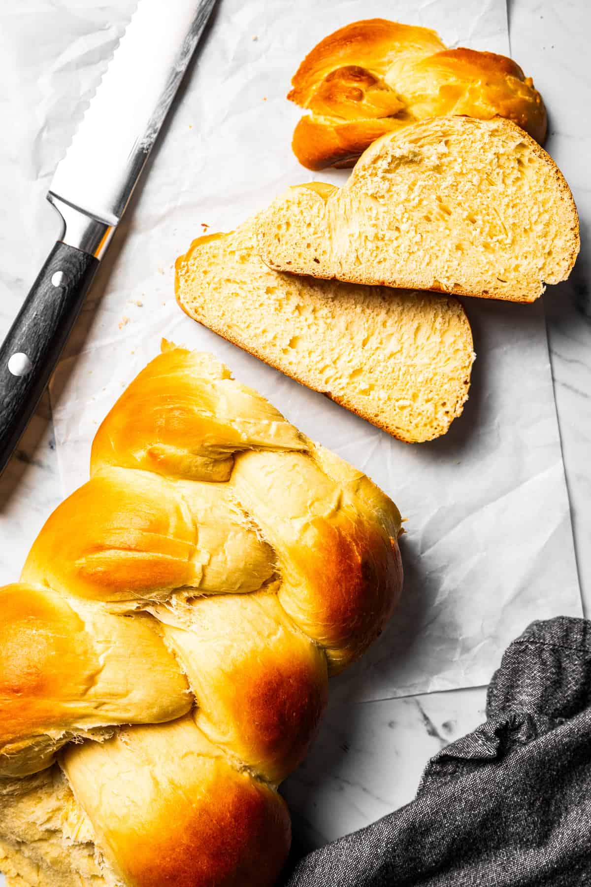 Overhead view of challah next to a bread knife with slices cut from the end.