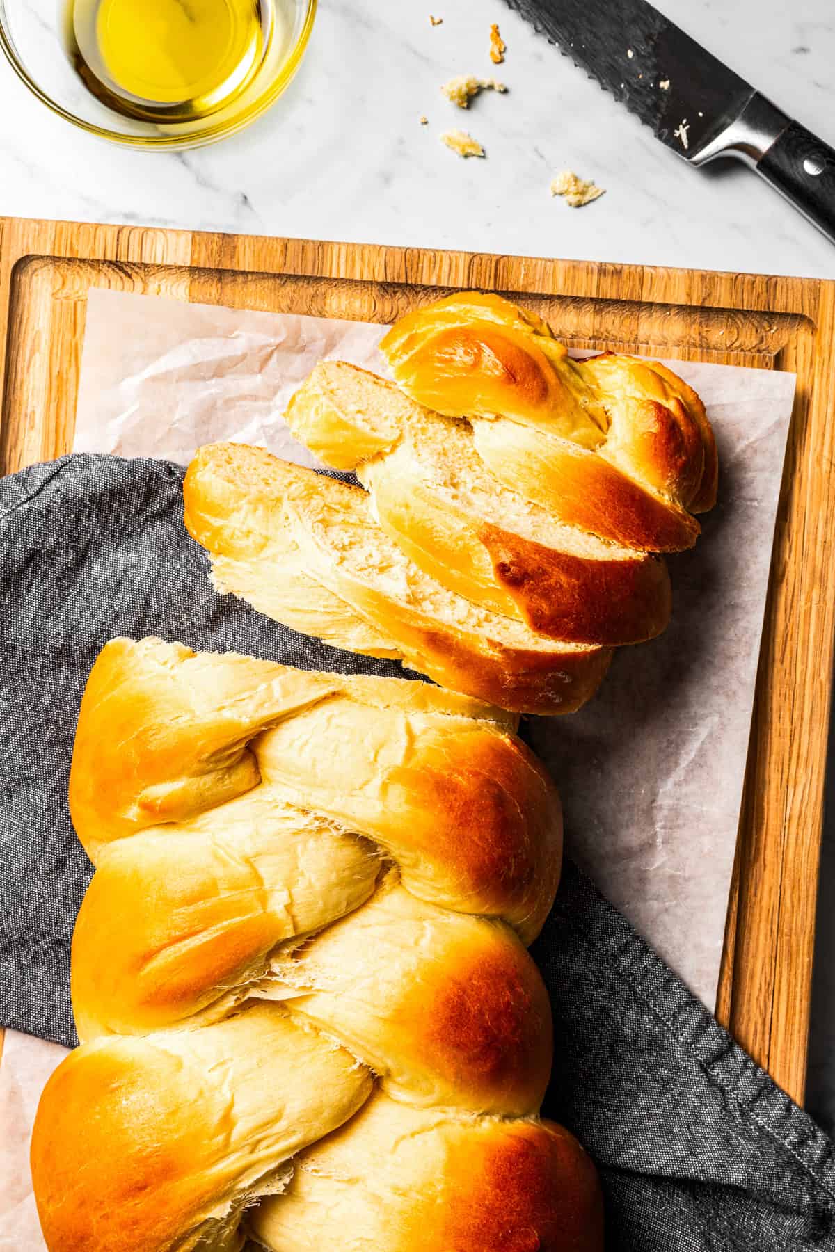 Challah loaf on a wooden cutting board with slices cut from the end.