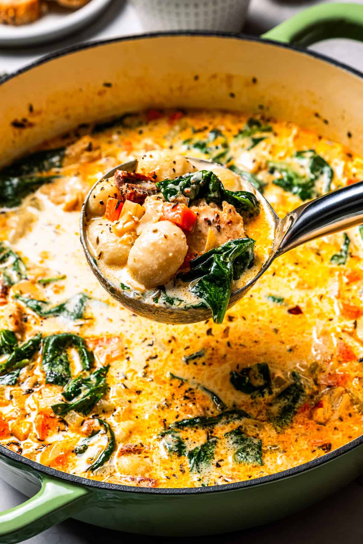 This chicken gnocchi soup is even better than the Olive Garden! It's ready in 20 minutes, extra creamy, and packed with flavorful ingredients. A ladle scooping out chicken soup with gnocchi.