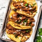 Carne asada tacos arranged in a pan.
