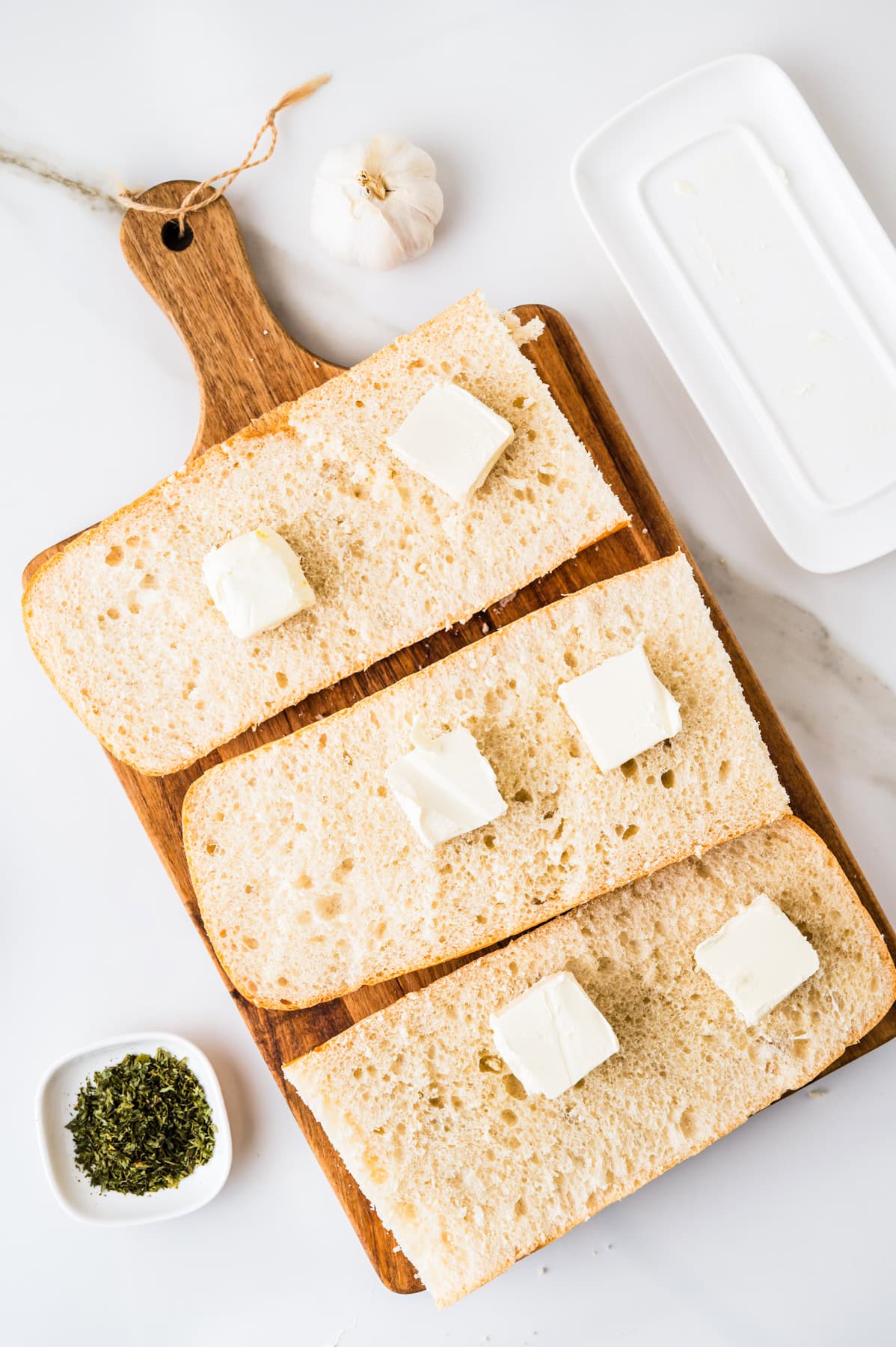 This tasty and easy air fryer garlic bread has crisp edges, a soft buttery center, and bold garlic flavor. A fast, oven-free side dish ready in 5 minutes. French bread cut in halves with pats of butter set over each slice.