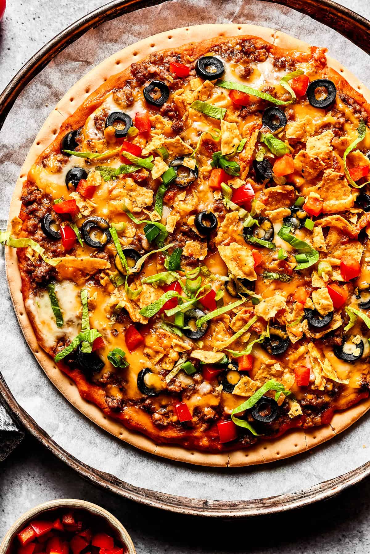 Weekly Meal Plan Round pizza topped with taco ingredients like ground beef, refried beans, olives, and cheese.