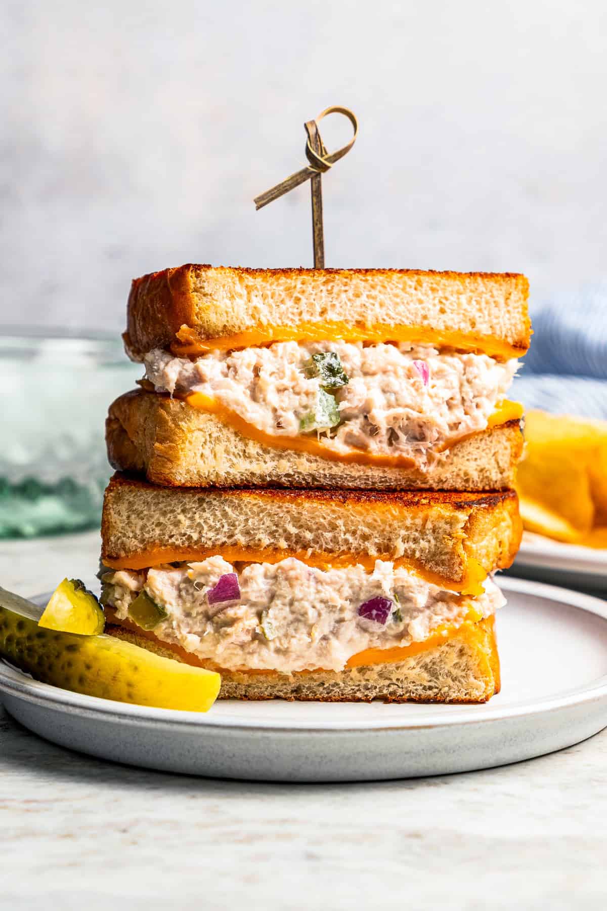 Two halves of a tuna melt stacked on a plate.