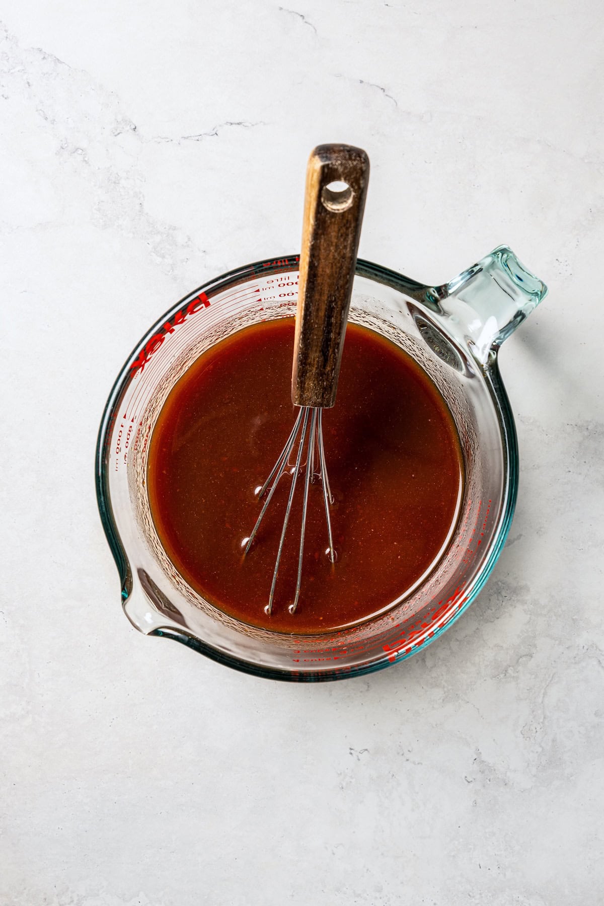 Beijing beef sauce in a glass measuring cup with a whisk.