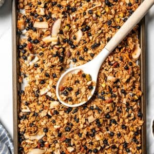 Overhead view of a spoon resting in a baking sheet of baked homemade granola.