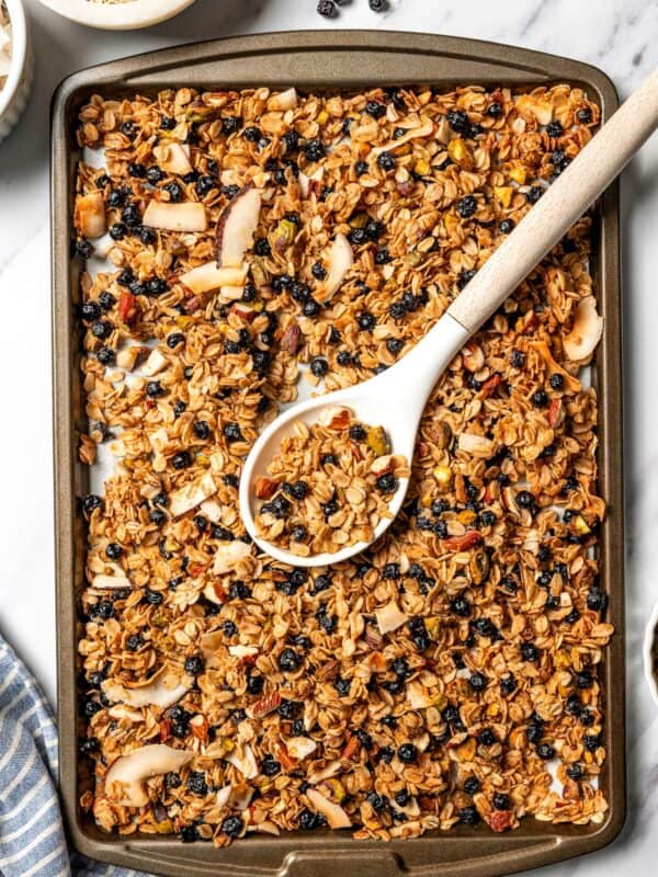 Overhead view of a spoon resting in a baking sheet of baked homemade granola.