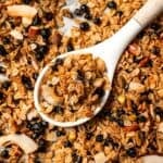 Overhead view of a spoon resting in a baking sheet of baked homemade granola.