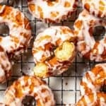 Overhead view of assorted glazed sour cream donuts on a wire rack.