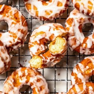 Overhead view of assorted glazed sour cream donuts on a wire rack.