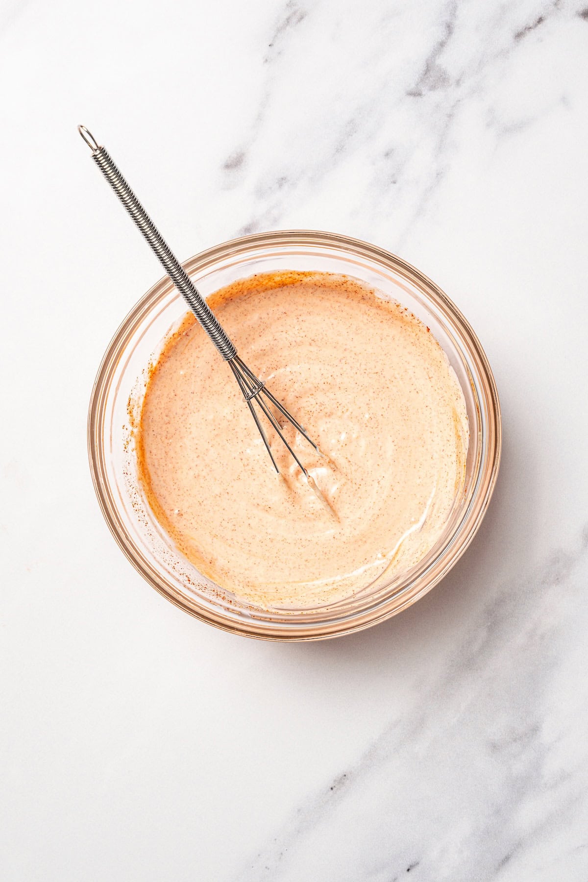 Spicy mayo in a bowl with a whisk.