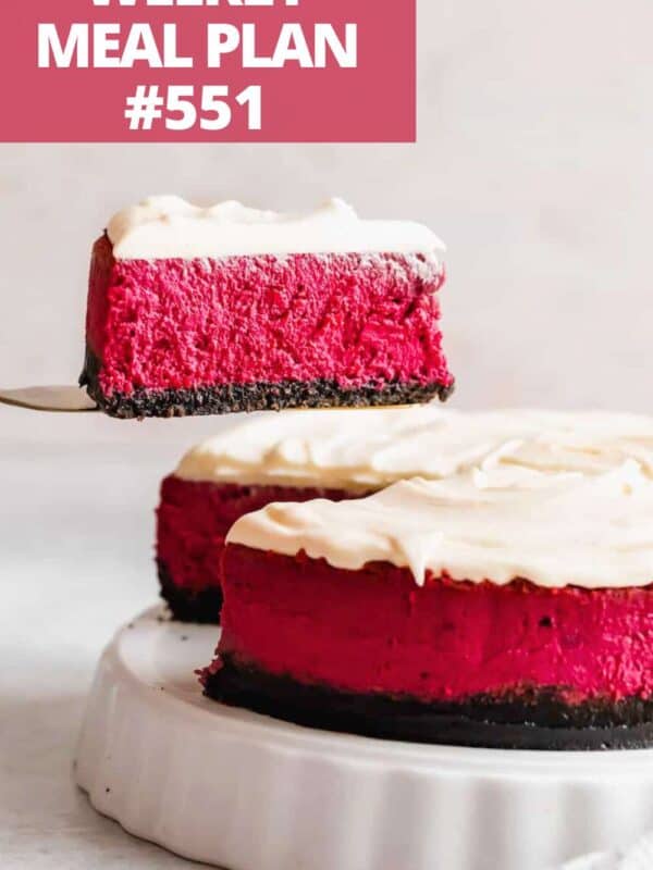 A cake server pulling up a slice of red velvet cheesecake from a whole cheesecake.