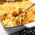 Serving spoon scooping out mac and cheese from a casserole dish.