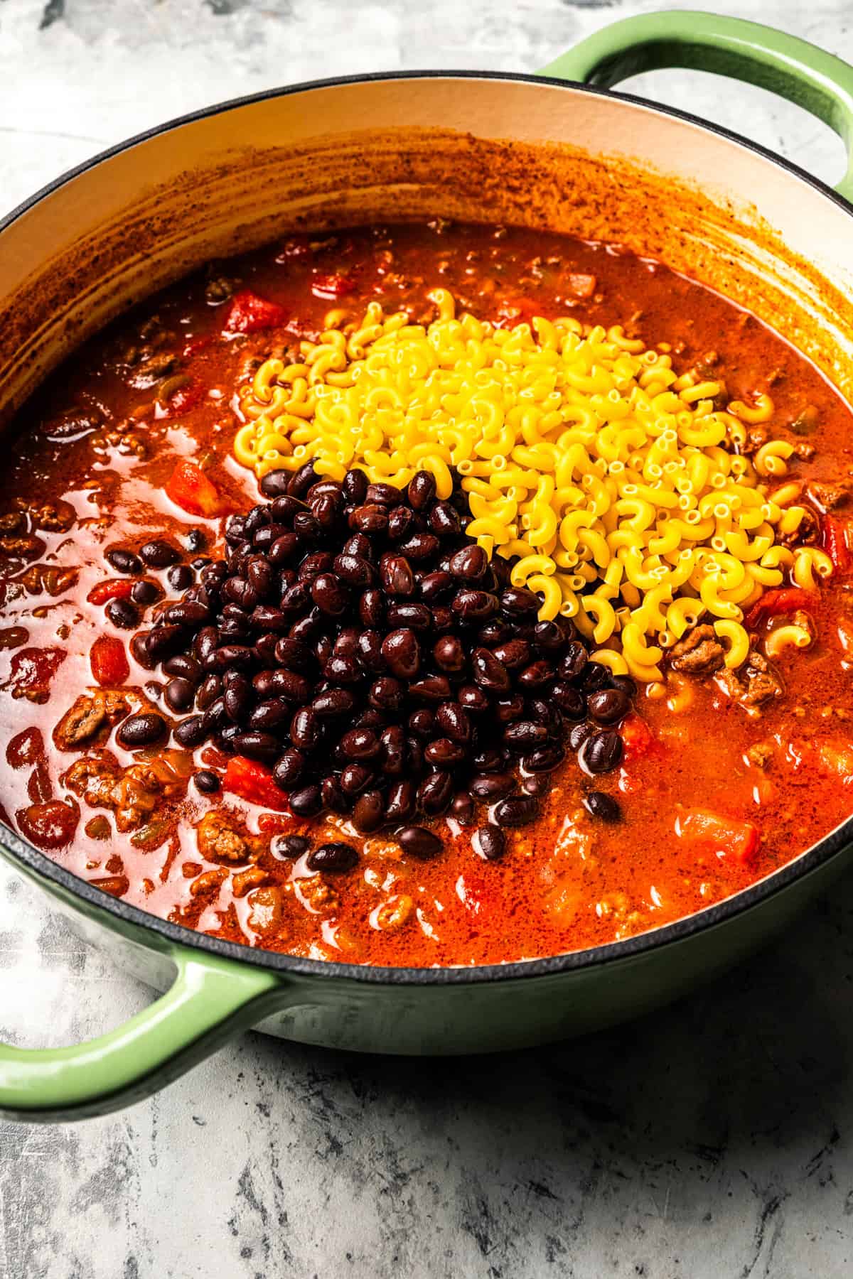 Elbow macaroni and black beans in a pot of chili.