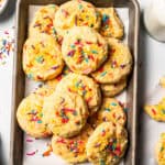 Funfetti cookies with sprinkles piled on a baking sheet.