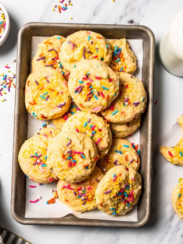 Funfetti cookies with sprinkles piled on a baking sheet.