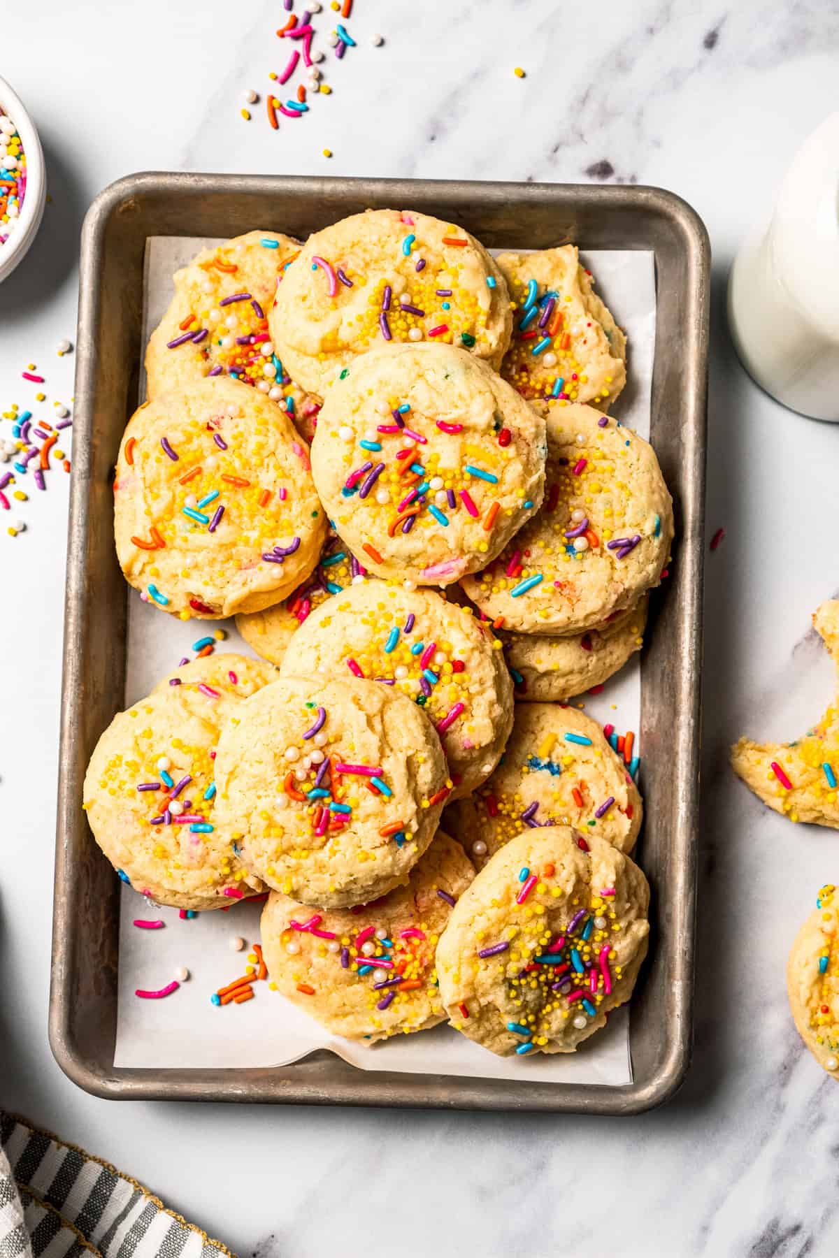 Funfetti cookies with sprinkles piled on a baking sheet.