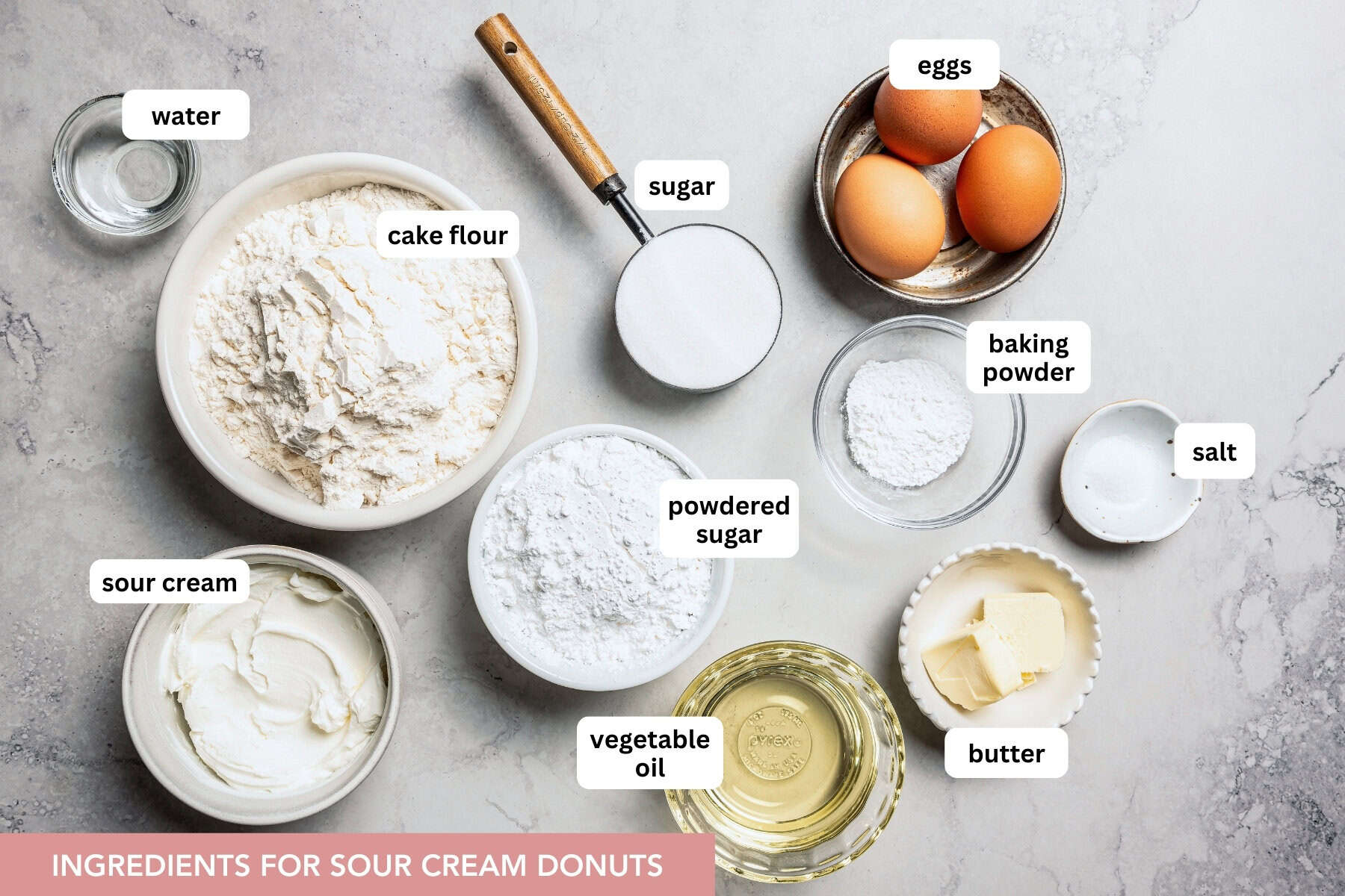 These old-fashioned sour cream donuts are soft and cakey beneath a golden crust coated in creamy vanilla glaze. No yeast or rising time! Sour cream donuts ingredients with text labels overlaying each ingredient.