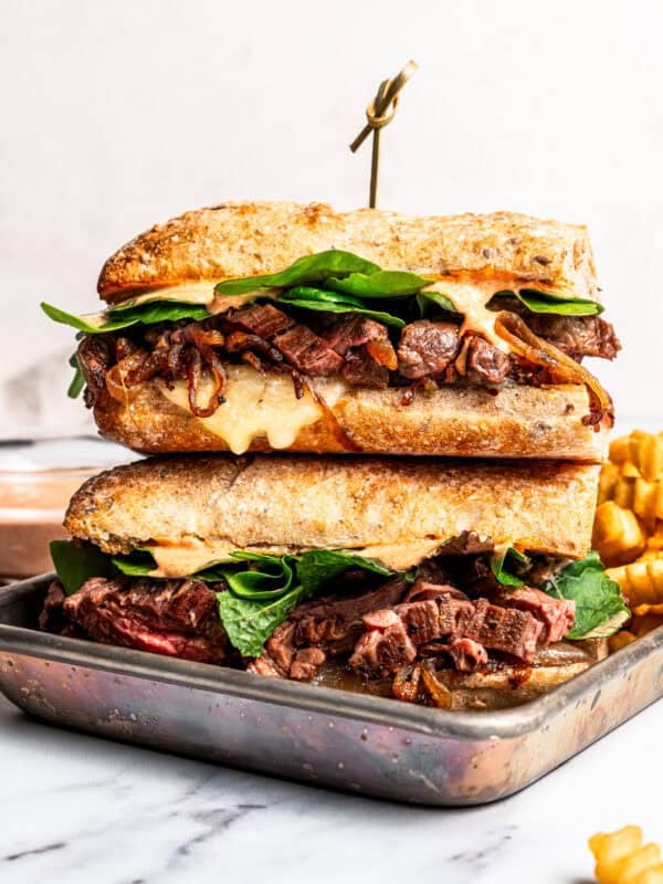 Two halves of a steak sandwich stacked on a tray.
