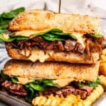 Two halves of a steak sandwich stacked on a tray.